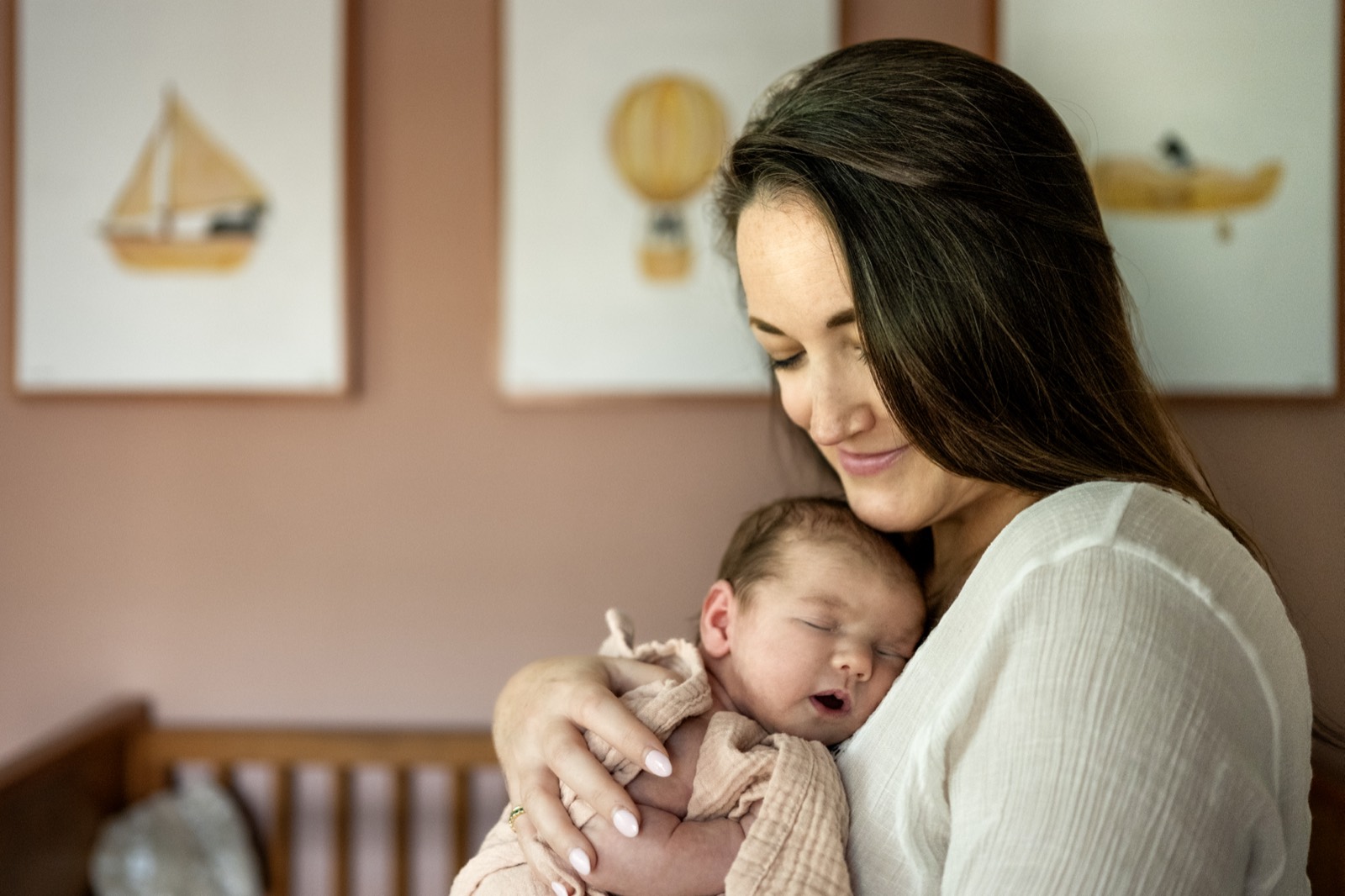 A Dallas mother holding her sleeping newborn cheek-to-cheek in the nursery during an in-home documentary session